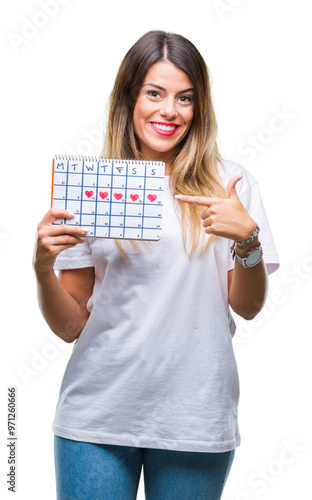 Young beautiful woman holding menstruation calendar over isolated background very happy pointing with hand and finger