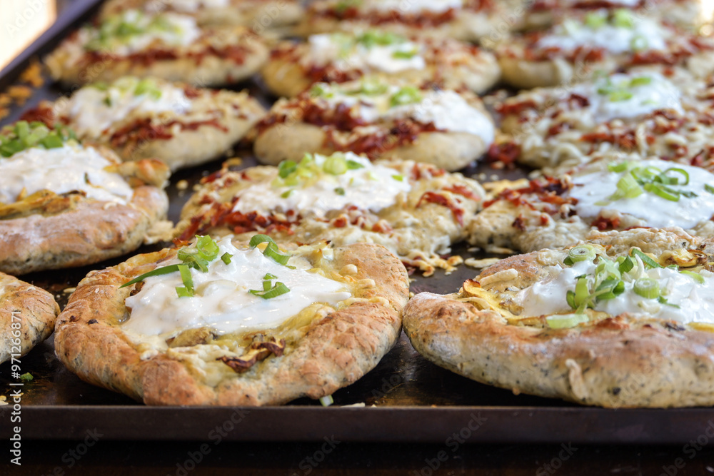 Baking tray with fresh hot langos, Hungarian flatbread variously filled with mushrooms or bacon and sour cream, finger food on an outdoor festival market, selected focus Baking tray with fresh hot langos, Hungarian flatbread variously filled with mushrooms or bacon and sour cream, finger food on an outdoor festival market, selected focus