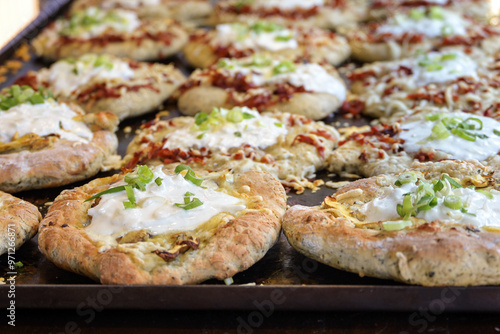 Baking tray with fresh hot langos, Hungarian flatbread variously filled with mushrooms or bacon and sour cream, finger food on an outdoor festival market, selected focus photo