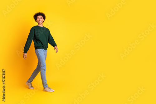 Full body portrait of nice young man walk empty space ad wear sweater isolated on yellow color background