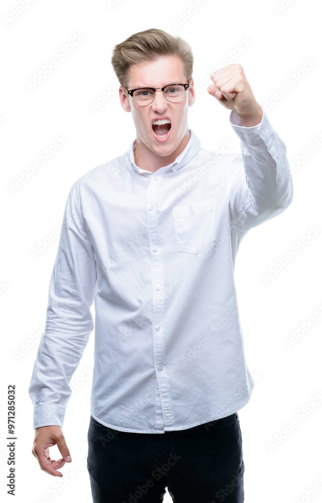 Naklejka premium Young handsome blond man angry and mad raising fist frustrated and furious while shouting with anger. Rage and aggressive concept.