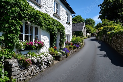 A rural road bordered by stone cottages, their ivy-covered walls and blooming flower gardens adding charm to the scene