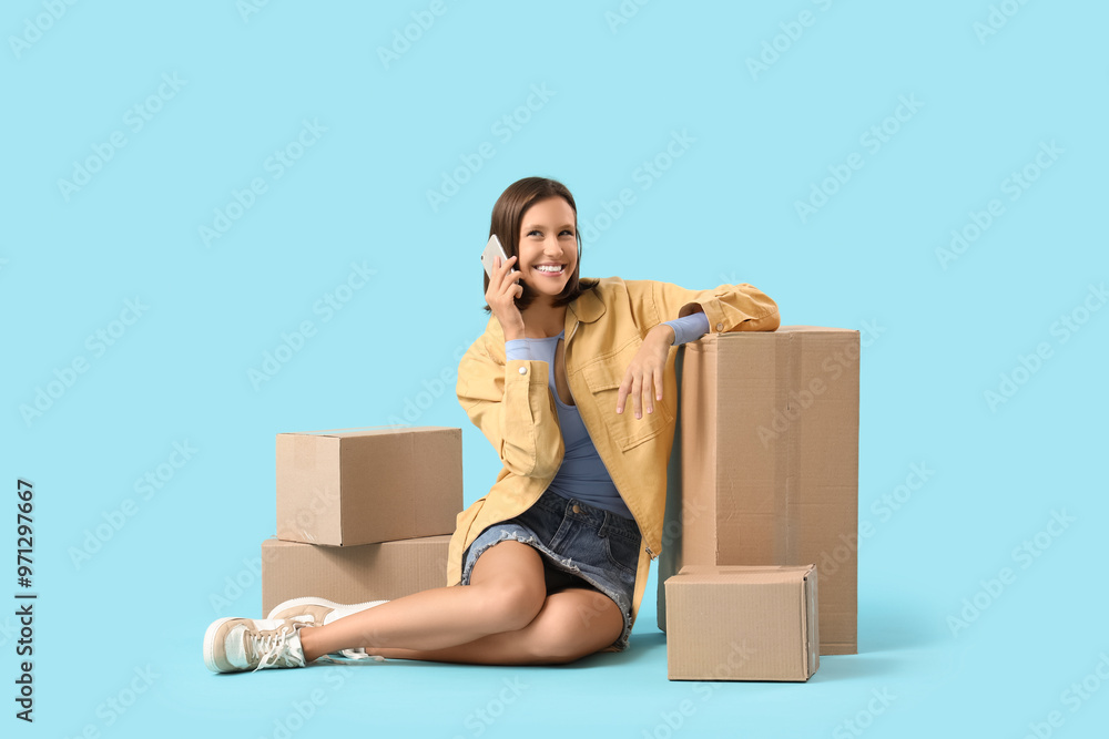 Beautiful young happy woman with parcels talking by mobile phone on blue background Beautiful young happy woman with parcels talking by mobile phone on blue background