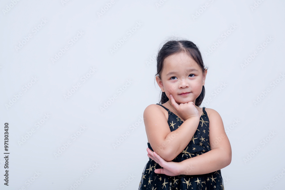A cute little asian girl posing pensively. Wearing a starry black dress. Isolated on a white background. A cute little asian girl posing pensively. Wearing a starry black dress. Isolated on a white background.