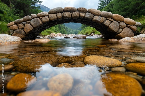 A stone bridge spanning a small river, built with smooth rocks that have stood the test of time