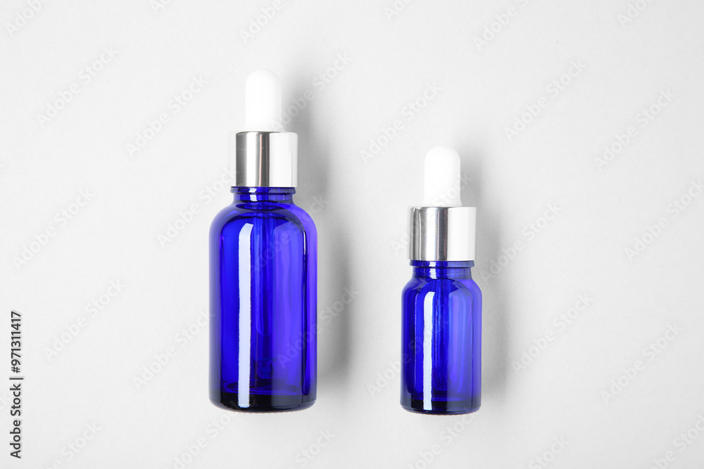 Essential oils in bottles on light background, top view Essential oils in bottles on light background, top view