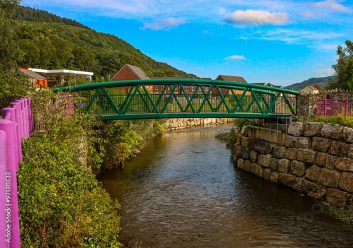 Photography Green metal bridge over a calm river with stone embankments  in Cardiff, Wales