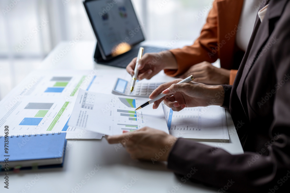 Business team analyzing financial charts and graphs on desk Business team analyzing financial charts and graphs on desk