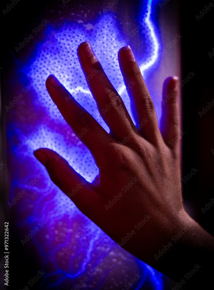 Hand touching glowing blue plasma ball with electric light effect Hand touching glowing blue plasma ball with electric light effect