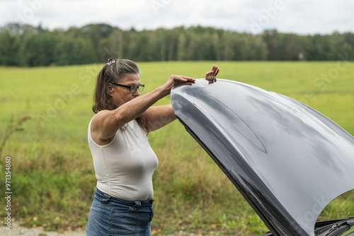 Obraz na płótnie Frau schließt die Motorhaube ihres Autos w salonie