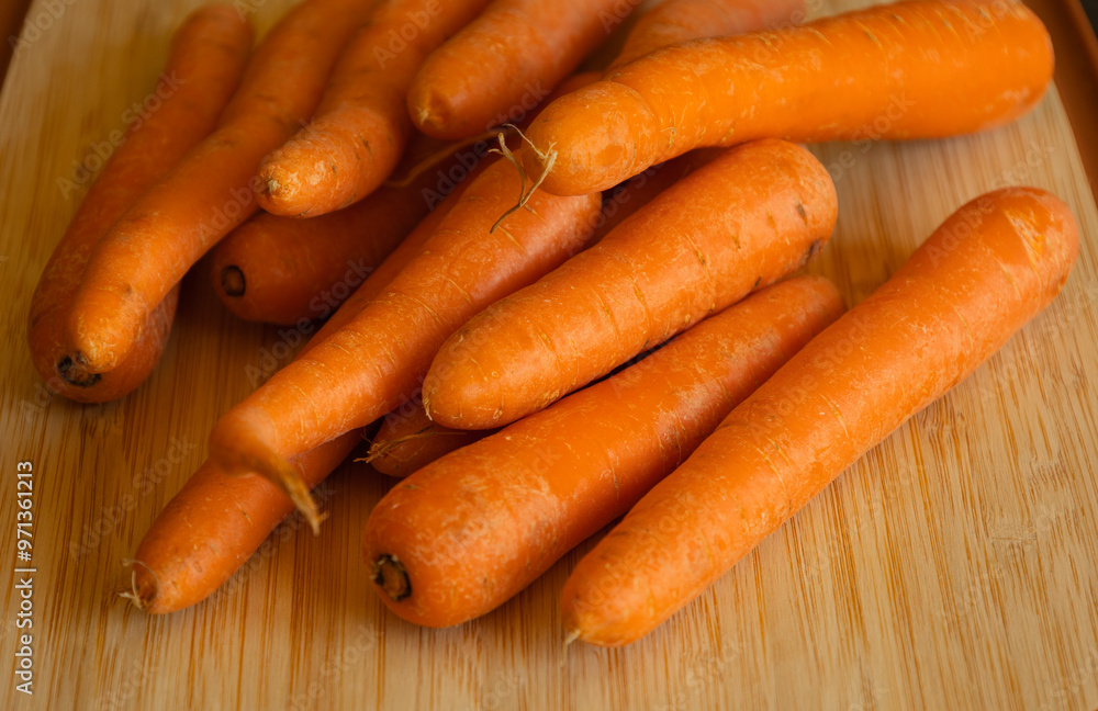 Bunch of Fresh Organic Carrots on a Wooden Chopping Board Close-Up Bunch of Fresh Organic Carrots on a Wooden Chopping Board Close-Up