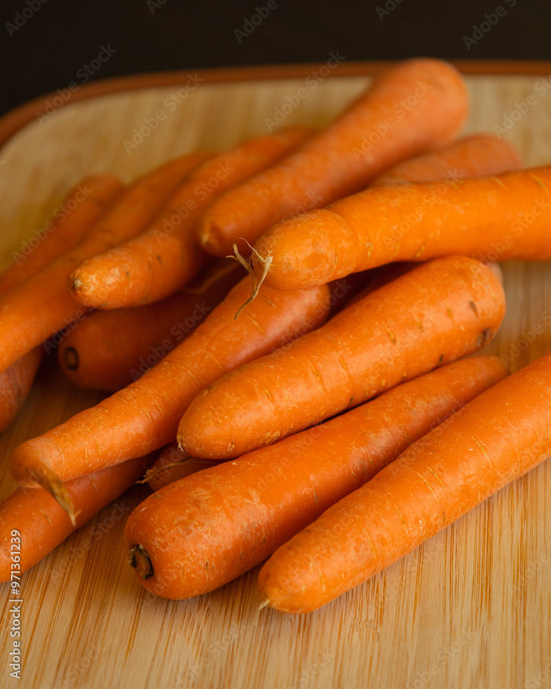 Bunch of Fresh Organic Carrots on a Wooden Chopping Board Close-Up Bunch of Fresh Organic Carrots on a Wooden Chopping Board Close-Up