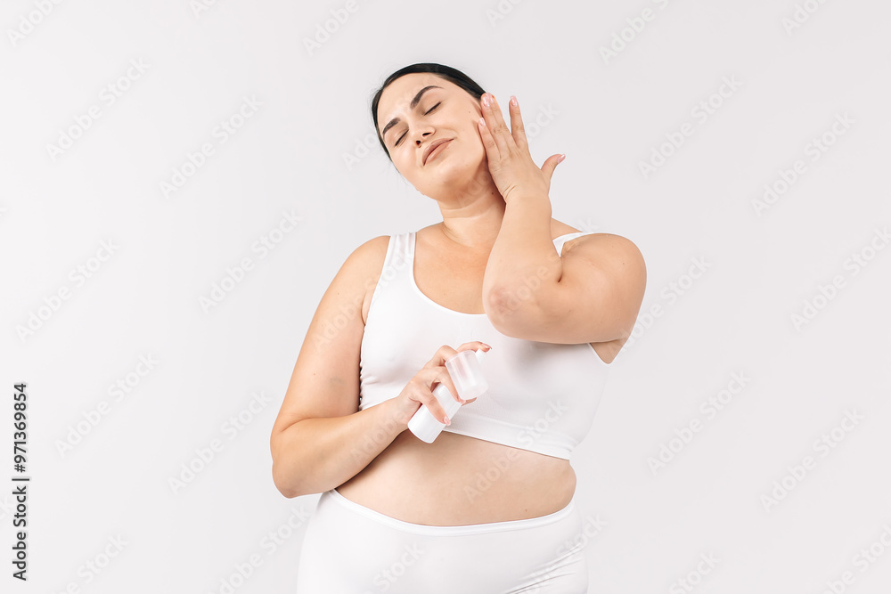 Young, beautiful brunette with curvy figure using skincare products on a white background. Perfect for promoting skincare, emphasizing confidence and beauty with your products. Young, beautiful brunette with curvy figure using skincare products on a white background. Perfect for promoting skincare, emphasizing confidence and beauty with your products.