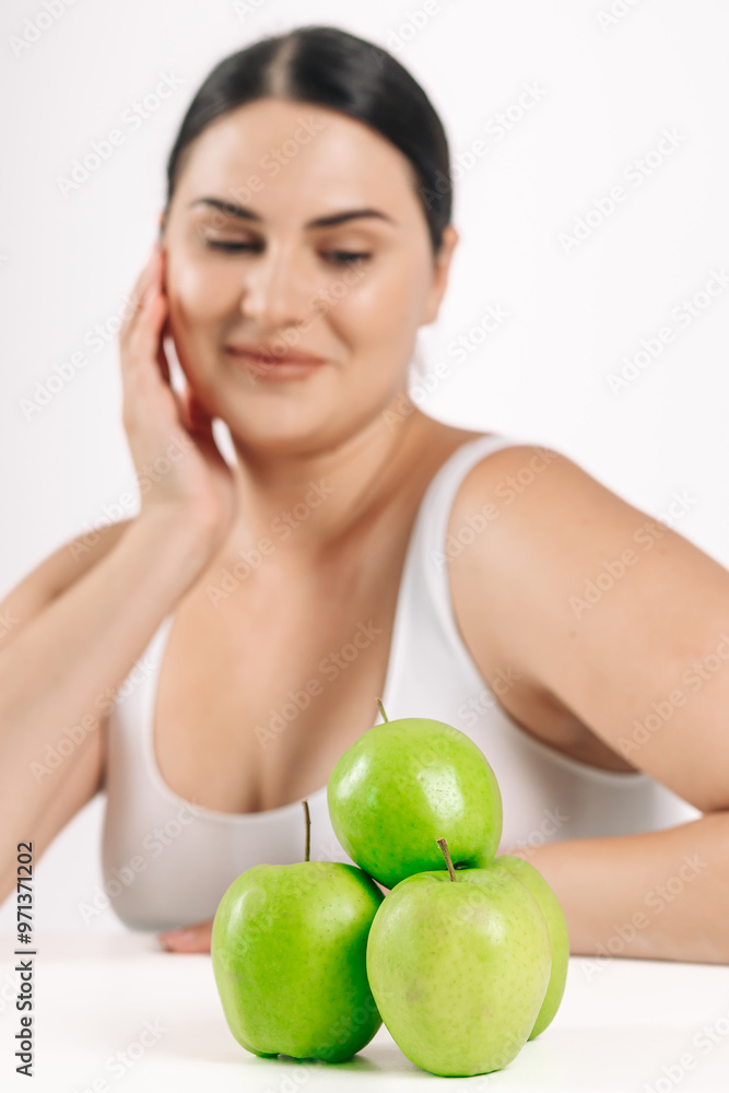 Young woman on a light background next to fresh green apples. Perfect for promoting healthy eating, highlighting the freshness and naturalness of your choice. Young woman on a light background next to fresh green apples. Perfect for promoting healthy eating, highlighting the freshness and naturalness of your choice.