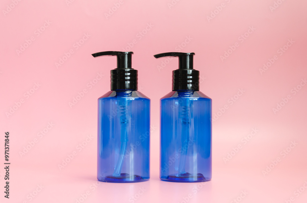 two plastic translucent blue bottles isolated on pink background. template, cosmetic dispenser two plastic translucent blue bottles isolated on pink background. template, cosmetic dispenser