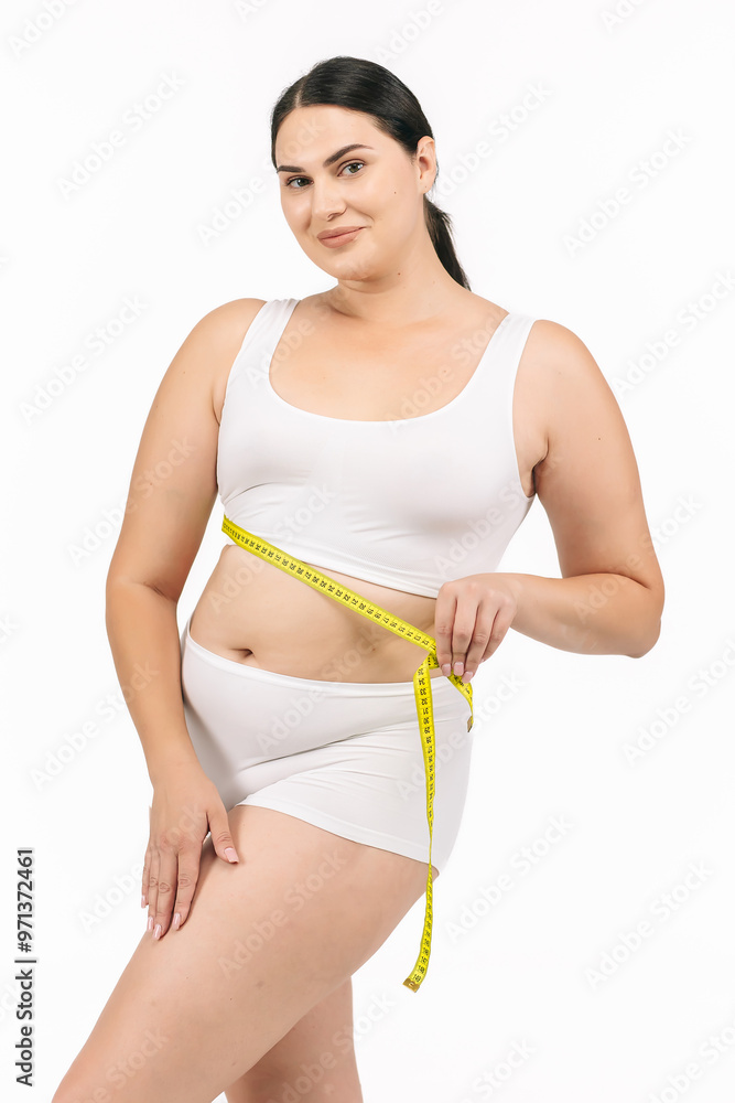 Young, beautiful woman with excess weight measuring her waist on a white background. Perfect for promoting weight loss programs and a healthy lifestyle, showcasing the journey to a slimmer figure Young, beautiful woman with excess weight measuring her waist on a white background. Perfect for promoting weight loss programs and a healthy lifestyle, showcasing the journey to a slimmer figure