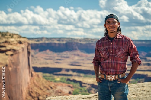 smiling happy young man standing on cliff with landscape behind him. Native American heritage day