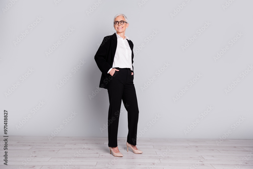 Full length photo of charming gorgeous successful lady wear trendy black suit look empty space isolated on grey color background Full length photo of charming gorgeous successful lady wear trendy black suit look empty space isolated on grey color background