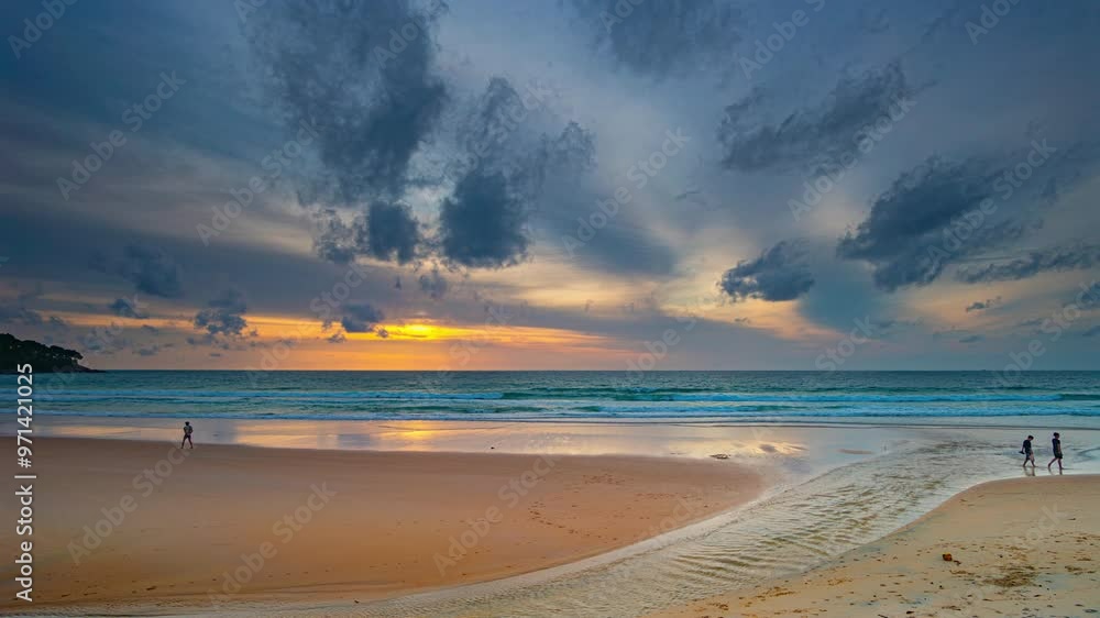 Time lapse A stunning sunset over the ocean with soft golden light reflecting on the water, featuring silhouettes of people walking along the shore.Water flows from a small stream into the sea.
