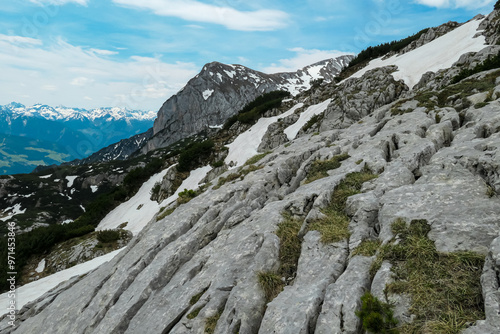 Large weathered rock formation with scenic view of majestic mountain peaks of Wasenspitze and Sinabell in Ramsau am Dachstein, Styria, Austria. Hiking trail in Austrian Alps. Schladminger Tauern