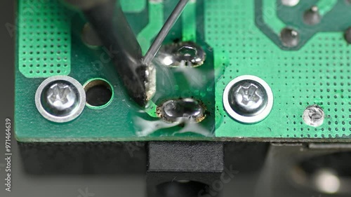 A man solders a circuit board with a soldering iron macro close up
