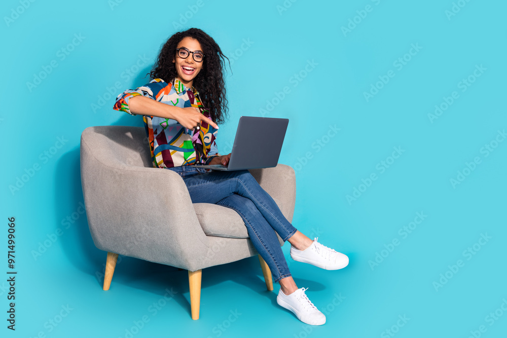 Photo of pretty lovely funny woman wear stylish clothes sit armchair showing netbook isolated on blue color background Photo of pretty lovely funny woman wear stylish clothes sit armchair showing netbook isolated on blue color background