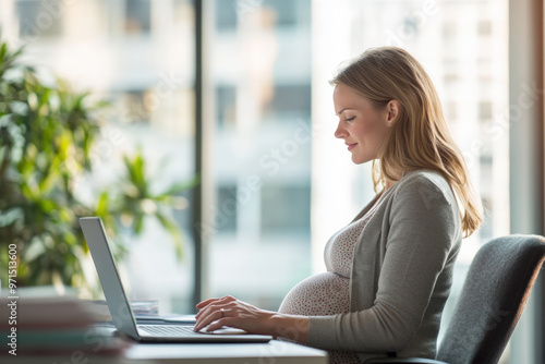 Pregnant businesswoman is sitting at her desk in the office working on her laptop