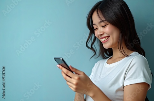 Portrait of a smiling happy girl with a smartphone in her hands on a blue pastel background