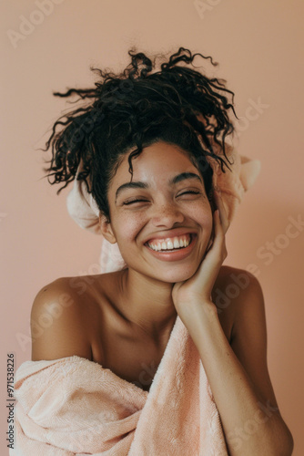 Joyful young black woman with towel smiling against beige background