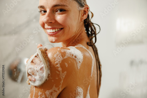 A woman enjoys a refreshing shower, joyfully using a foamfilled scrub brush to cleanse herself thoroughly photo