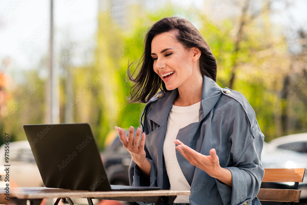Photo of charming positive woman wear grey trench smiling communicating modern gadget sitting cafeteria outdoors urban city street Photo of charming positive woman wear grey trench smiling communicating modern gadget sitting cafeteria outdoors urban city street