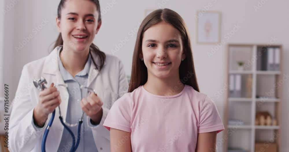 Happy smiling child girl in clinic for a medical checkup. Female doctor with stethoscope examining kid's lungs, breathing and heartbeat at hospital. Pediatrician checking a young patient. 4k video. Happy smiling child girl in clinic for a medical checkup. Female doctor with stethoscope examining kid's lungs, breathing and heartbeat at hospital. Pediatrician checking a young patient. 4k video.