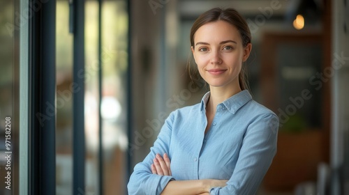 confident businesswoman portrait young professional in crisp blue shirt stands with arms crossed exuding poise and competence warm smile and direct gaze convey approachability and leadership