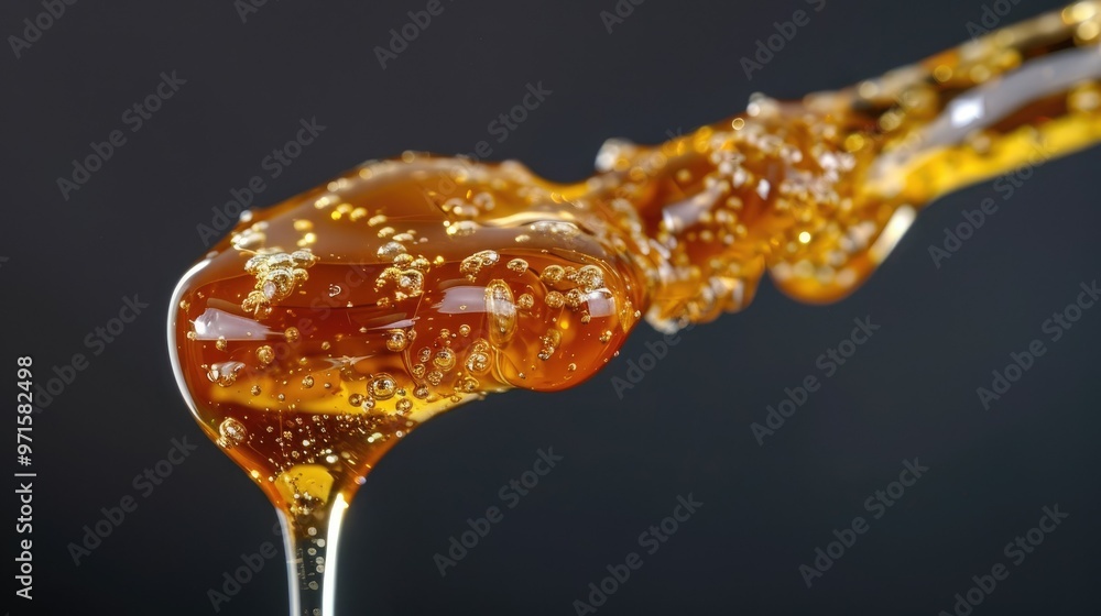 Honey dripping from the tip of a syringe Honey dripping from the tip of a syringe