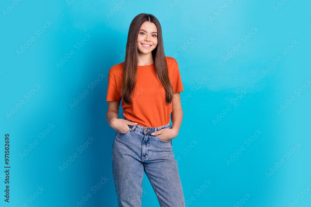 Photo portrait of lovely teen lady posing hands pockets model dressed stylish orange garment isolated on blue color background Photo portrait of lovely teen lady posing hands pockets model dressed stylish orange garment isolated on blue color background