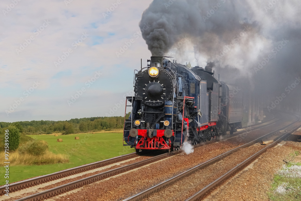 Obraz premium Retro Steam Locomotive Traveling Along Railroad Along Rural Fields