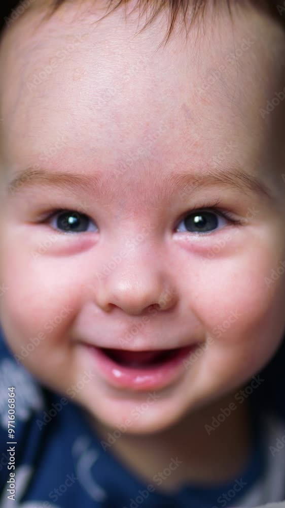 Cute boy looks down with astonishment. Beautiful Caucasian kid smiling with his toothless smile. Close up. Vertical video