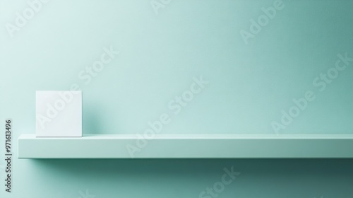 Minimalist scene featuring a white object on a shelf against a soft green wall.