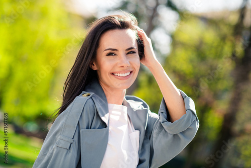 Portrait of beautiful young smiling hispanic attractive lady touch brunette hairstyle wearing gray coat walking outdoors sunny days relaxed in nature