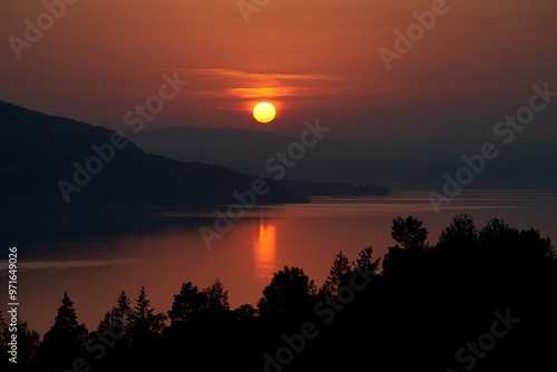 Sunset Over Tyrifjorden with a Sharp Yellow Sun, Dark Red Sky, and Black Forest Silhouette Reflected on the Water: A Dramatic and Serene Norwegian Landscape