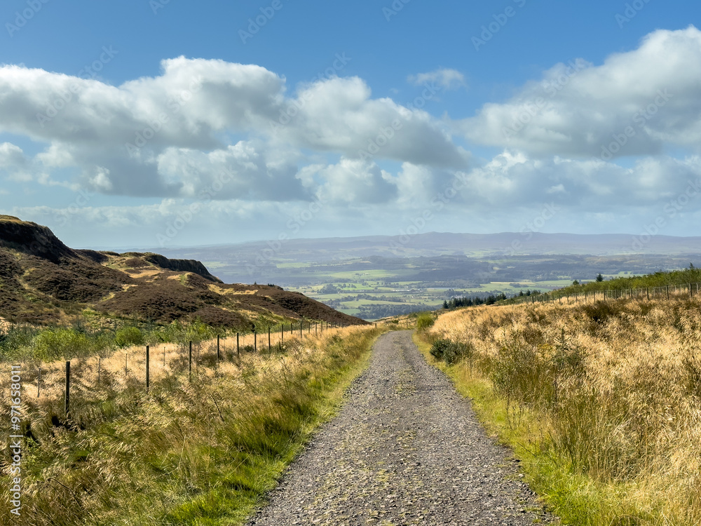Summer view path or track of heather and grass highlands in Scotland with water and rolling hills Summer view path or track of heather and grass highlands in Scotland with water and rolling hills
