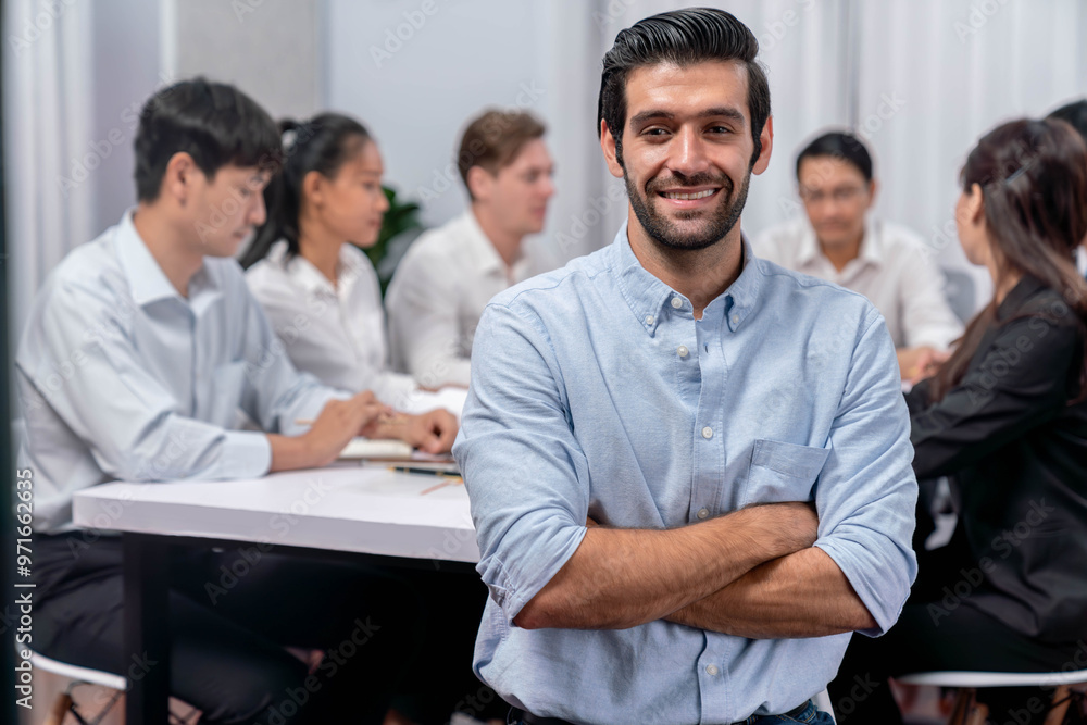 Confidence and happy smiling businessman portrait with background of his colleague and business team working in office. Office worker teamwork and positive workplace concept. Prudent Confidence and happy smiling businessman portrait with background of his colleague and business team working in office. Office worker teamwork and positive workplace concept. Prudent