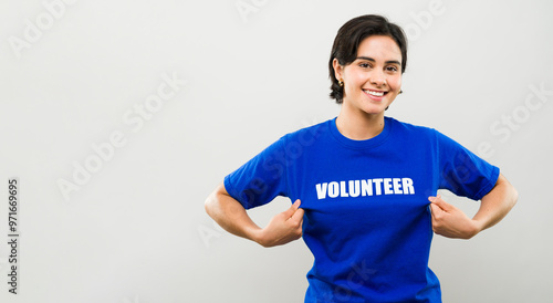 Young woman beaming with pride as she points to her volunteer t-shirt, representing the spirit of kindness and generosity in charity work and activism