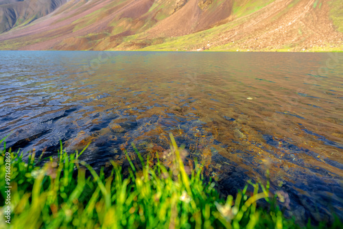 Chandratal lake, Moon Lake during Sunset with crystal clear water in between mountains surrounded by snowcapped mountains. photo