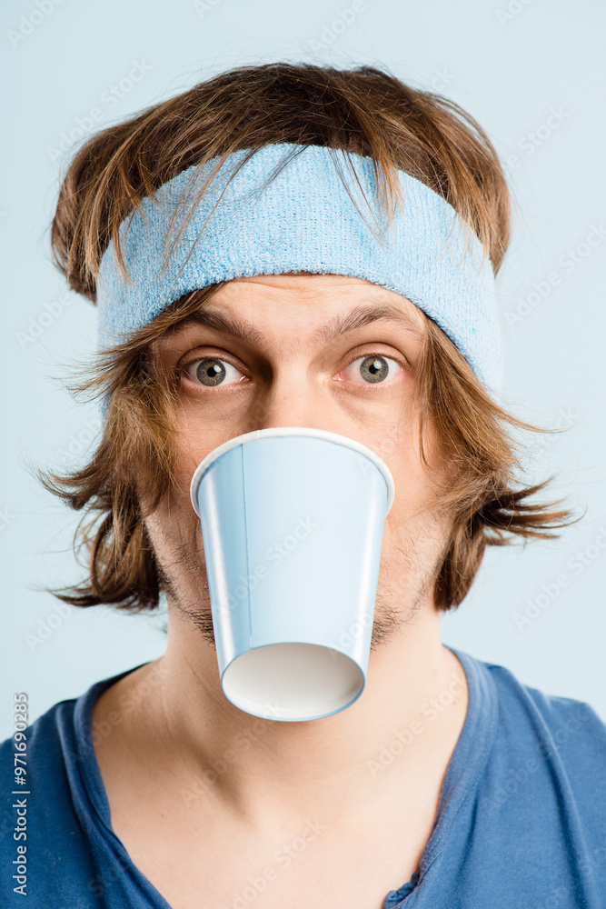 Funny, goofy and portrait of man with coffee cup in studio for fitness with retro headband for workout. Caffeine addict, crazy and athlete drinking cappuccino or latte with vintage exercise fashion. Funny, goofy and portrait of man with coffee cup in studio for fitness with retro headband for workout. Caffeine addict, crazy and athlete drinking cappuccino or latte with vintage exercise fashion.
