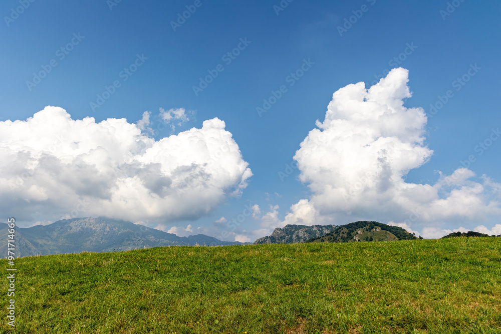 Mountain landscape with meadow, white clouds and blue sky Mountain landscape with meadow, white clouds and blue sky