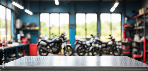 The empty stainless steel table top with blur background of Motorbike Repair Shop. For product display