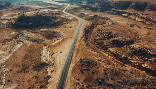 Deserted road cutting through a vast, isolated desert terrain, showcasing an expansive aerial view