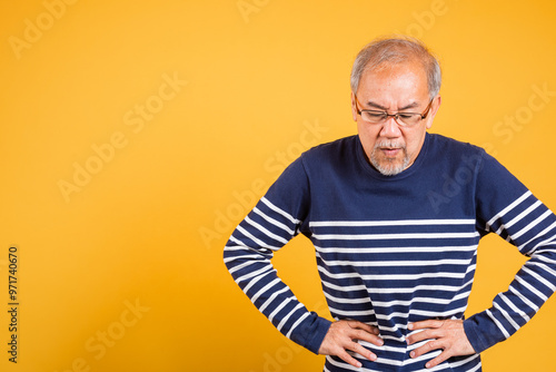 Fotografie Portrait Asian old man with glasses holds hands on abdomen he stomach ache studi