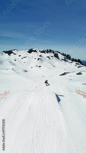 An Snowboarder doing line on grind box and Jumping High on a Beautiful Snowy Slope with Joy on ski reset in Austrian Alps, portrait orientation